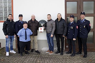 Sponsorenbild Defibrillator 2024 Vertreter der Feuerwehr Amerbach mit den Sponsoren vor dem neuen Defibrillator am Feuerwehrhaus. Personen im Bild von links nach rechts: Rainer Fackler, Michael Hönle, Sebastian Holzner, Konrad Mayer, Klaus Hönle, Josef Fackler, Michael Schneid, Daniel Trollmann