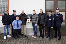 Vertreter der Feuerwehr Amerbach mit den Sponsoren vor dem neuen Defibrillator am Feuerwehrhaus. Personen im Bild von links nach rechts: Rainer Fackler, Michael Hönle, Sebastian Holzner, Konrad Mayer, Klaus Hönle, Josef Fackler, Michael Schneid, Daniel Trollmann